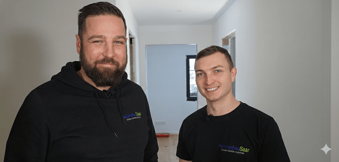 Gruppe von acht Bauarbeitern in Jacken, die lächeln und posieren.